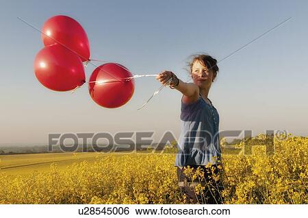 Girl carrying balloons in field View Large Photo Image Stock Photograph - Girl carrying balloons in field. Fotosearch