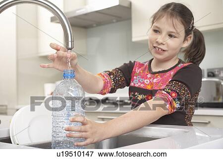 Girl filling up water bottle in kitchen View Large Photo Image Stock Photo - Girl filling up water bottle in kitchen. Fotosearch