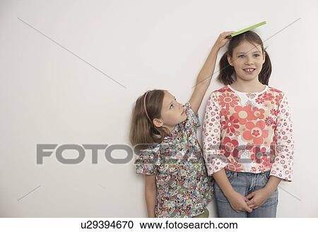 Girl measuring taller sister View Large Photo Image Stock Image - Girl measuring taller sister. Fotosearch