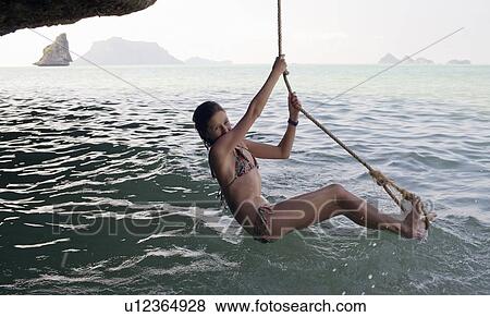 Stock Photo - Girl playing on rope over water. Fotosearch