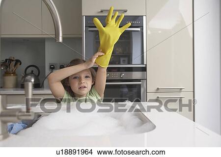 Picture - Girl pulling on rubber glove at sink. Fotosearch