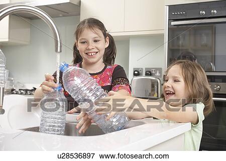 Girls filling up water bottle in kitchen View Large Photo Image Stock Photo - Girls filling up water bottle in kitchen. Fotosearch