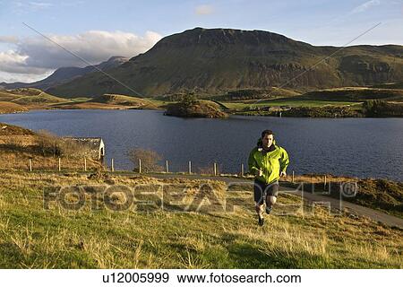 Hiker running up grassy hillside View Large Photo Image Stock Photo - Hiker running up grassy hillside. Fotosearch