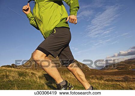 Stock Photo - Hiker running up grassy hillside. Fotosearch