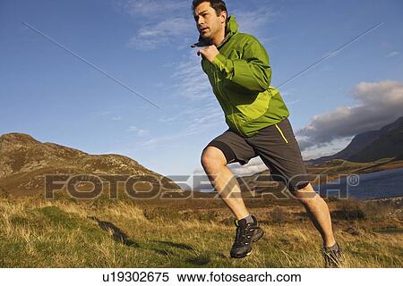 Stock Photography - Hiker running up grassy hillside. Fotosearch