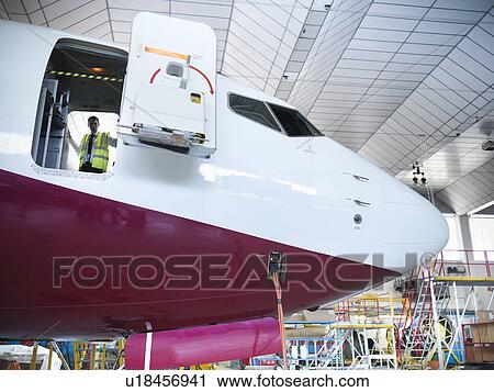 Stock Image - Inspector on docked airplane. Fotosearch