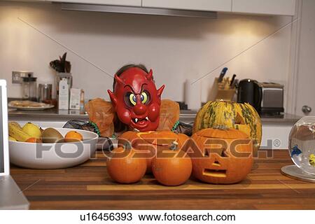 Stock Image - Jack-o-lanterns and mask in kitchen. Fotosearch