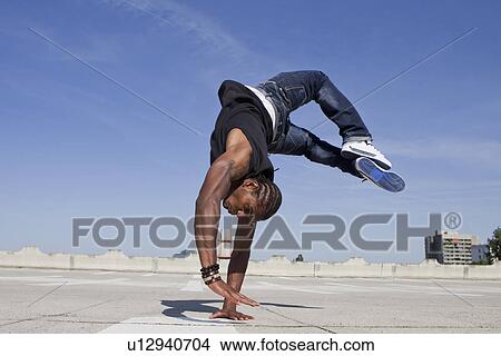 Picture - Man doing handstand on rooftop. Fotosearch