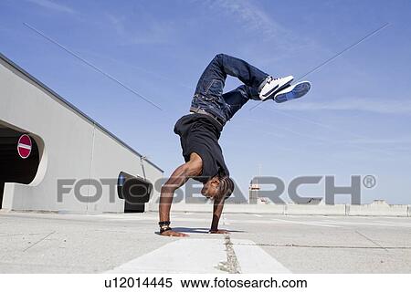 Stock Photography - Man doing handstand on rooftop. Fotosearch