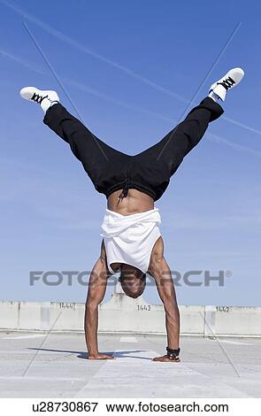 Man doing handstand on urban rooftop View Large Photo Image Stock Photo - Man doing handstand on urban rooftop. Fotosearch