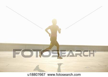 Stock Photo - Man running on rooftop. Fotosearch