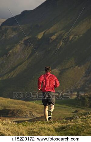 Stock Image - Man running on rural mountain road. Fotosearch