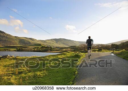 Stock Photo - Man running on rural road. Fotosearch