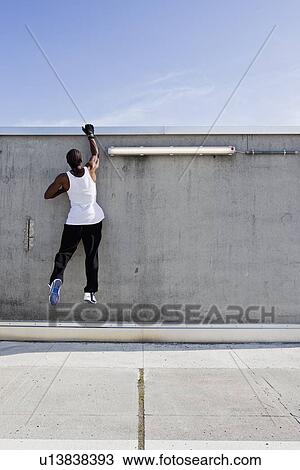 Man scaling wall on city street View Large Photo Image Stock Image - Man scaling wall on city street. Fotosearch