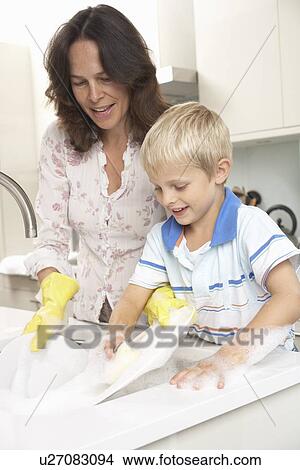 Mother and son washing dishes in kitchen View Large Photo Image Picture - Mother and son washing dishes in kitchen. Fotosearch
