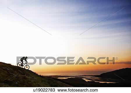 Mountain biker riding down hillside View Large Photo Image Stock Image - Mountain biker riding down hillside. Fotosearch