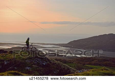 Mountain biker standing on hilltop View Large Photo Image Stock Photo - Mountain biker standing on hilltop. Fotosearch