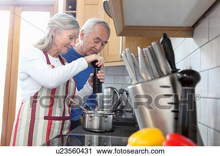 Stock Image - Older couple cooking together in kitchen. Fotosearch