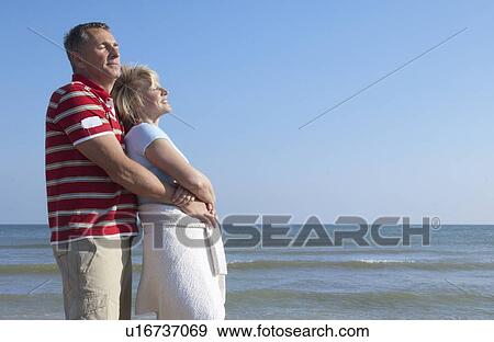 Stock Photo - Older couple hugging on beach. Fotosearch