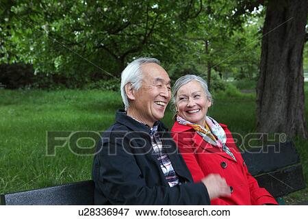 Stock Photo - Older couple sitting on park bench. Fotosearch