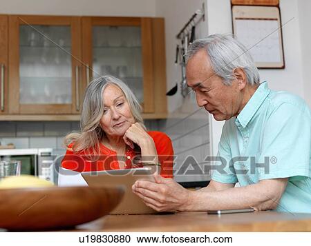 Stock Image - Older couple using tablet computer. Fotosearch