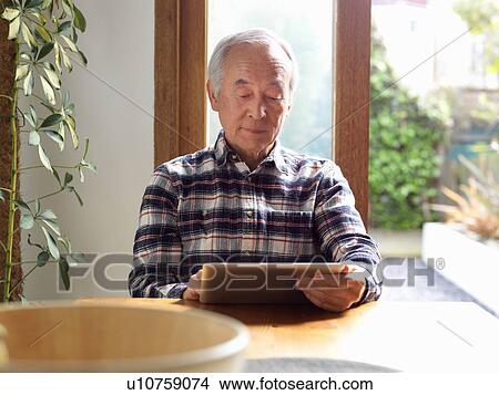 Picture - Older man using tablet computer. Fotosearch
