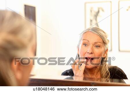 Older woman applying makeup in mirror View Large Photo Image Stock Photograph - Older woman applying makeup in mirror. Fotosearch