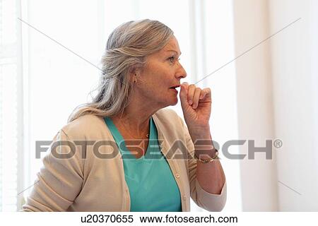 Stock Photography - Older woman coughing into her hand. Fotosearch