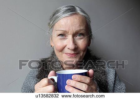 Stock Image - Older woman drinking coffee indoors. Fotosearch