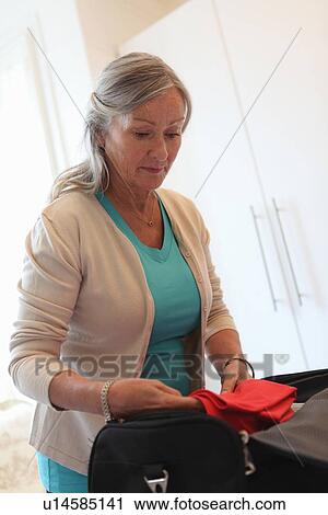 Stock Image - Older woman packing a suitcase. Fotosearch