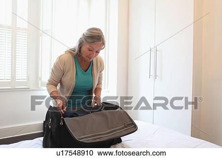 Older woman packing a suitcase View Large Photo Image Stock Image - Older woman packing a suitcase. Fotosearch