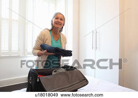 Stock Photo - Older woman packing a suitcase. Fotosearch