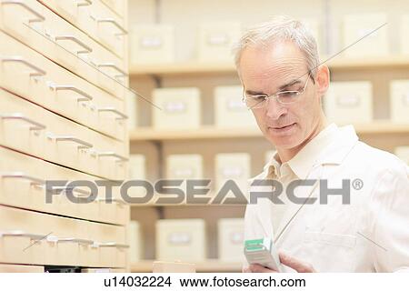 Picture - Pharmacist examining box of pills. Fotosearch