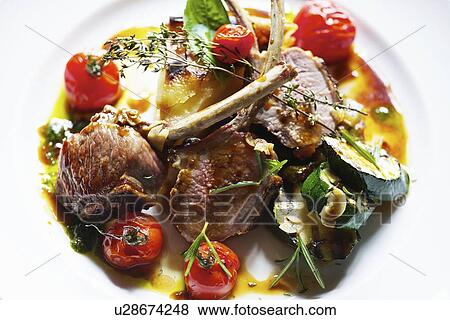 Stock Photo - Plate of lamb cutlets with tomatoes. Fotosearch