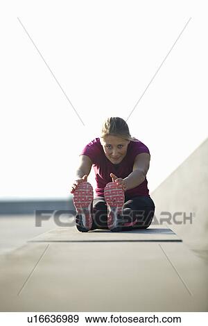 Stock Photo - Runner stretching on rooftop. Fotosearch