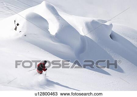 Stock Image - Skier coasting on snowy slope. Fotosearch