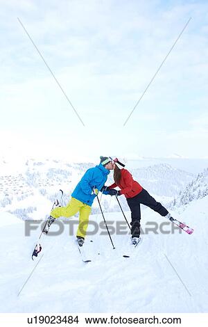 Picture - Skiers kissing on snowy mountaintop. Fotosearch