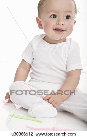 Stock Image - Smiling baby sitting on floor. Fotosearch
