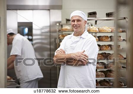 Stock Image - Smiling chef standing in kitchen. Fotosearch