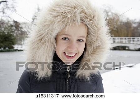 Stock Photo - Smiling girl wearing fur hood in snow. Fotosearch