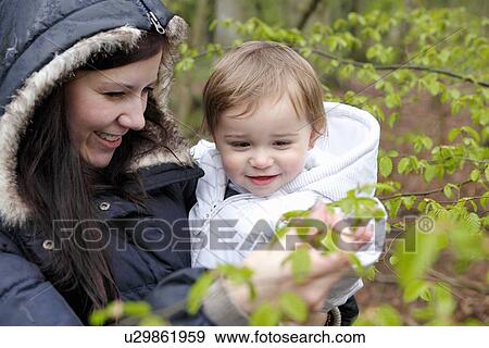 Smiling mother carrying son in forest View Large Photo Image Stock Photo - Smiling mother carrying son in forest. Fotosearch