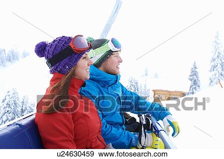 Stock Photo - Smiling skiers riding ski lift. Fotosearch