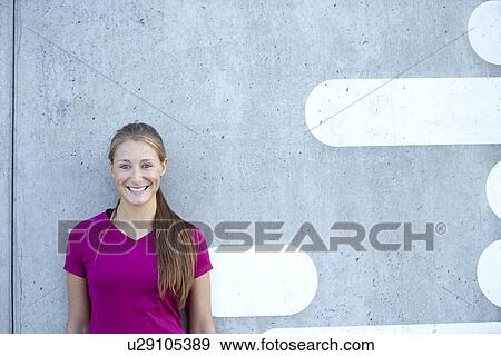 Smiling woman leaning against wall View Large Photo Image Stock Photo - Smiling woman leaning against wall. Fotosearch