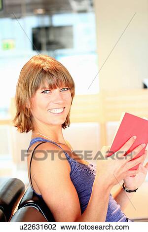 Smiling woman reading book in airport View Large Photo Image Stock Image - Smiling woman reading book in airport. Fotosearch