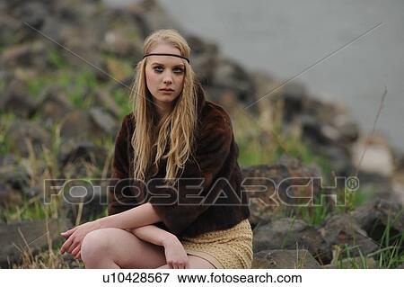 Stock Photo - Teenage girl sitting on rocks. Fotosearch