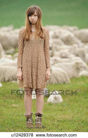 Stock Photo - Teenage girl standing in field of sheep. Fotosearch