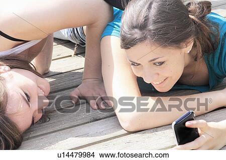 Teenage girls using cell phone outdoors View Large Photo Image Picture - Teenage girls using cell phone outdoors. Fotosearch