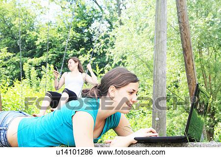 Teenage girls using technology outdoors View Large Photo Image Stock Photograph - Teenage girls using technology outdoors. Fotosearch