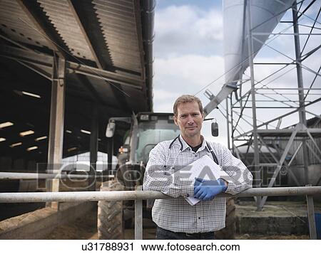 Stock Image - Veterinarian standing outside barn. Fotosearch