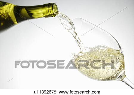 Stock Photography - White wine pouring into glass. Fotosearch
